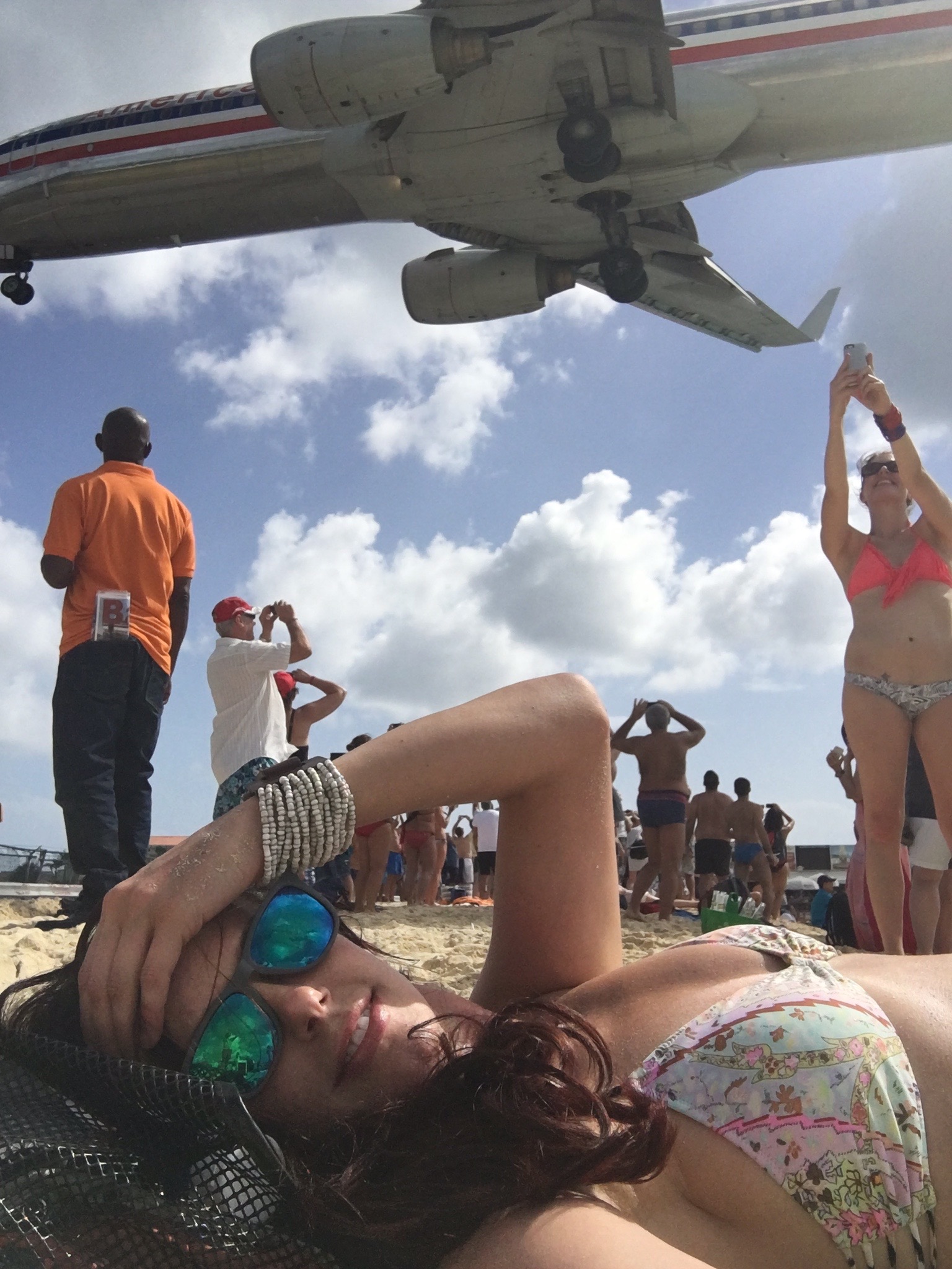 a woman lying on the beach with a plane in the background