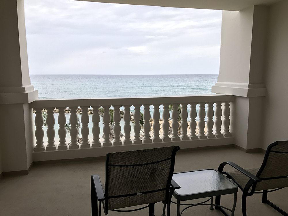 a chair and table on a balcony overlooking the ocean