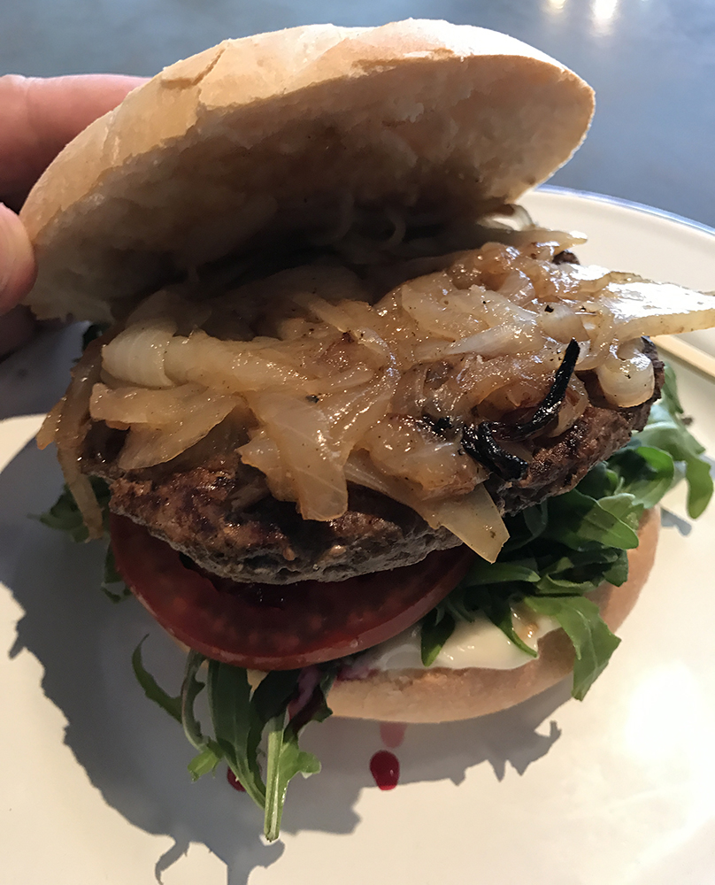 a burger with onions and lettuce on a plate