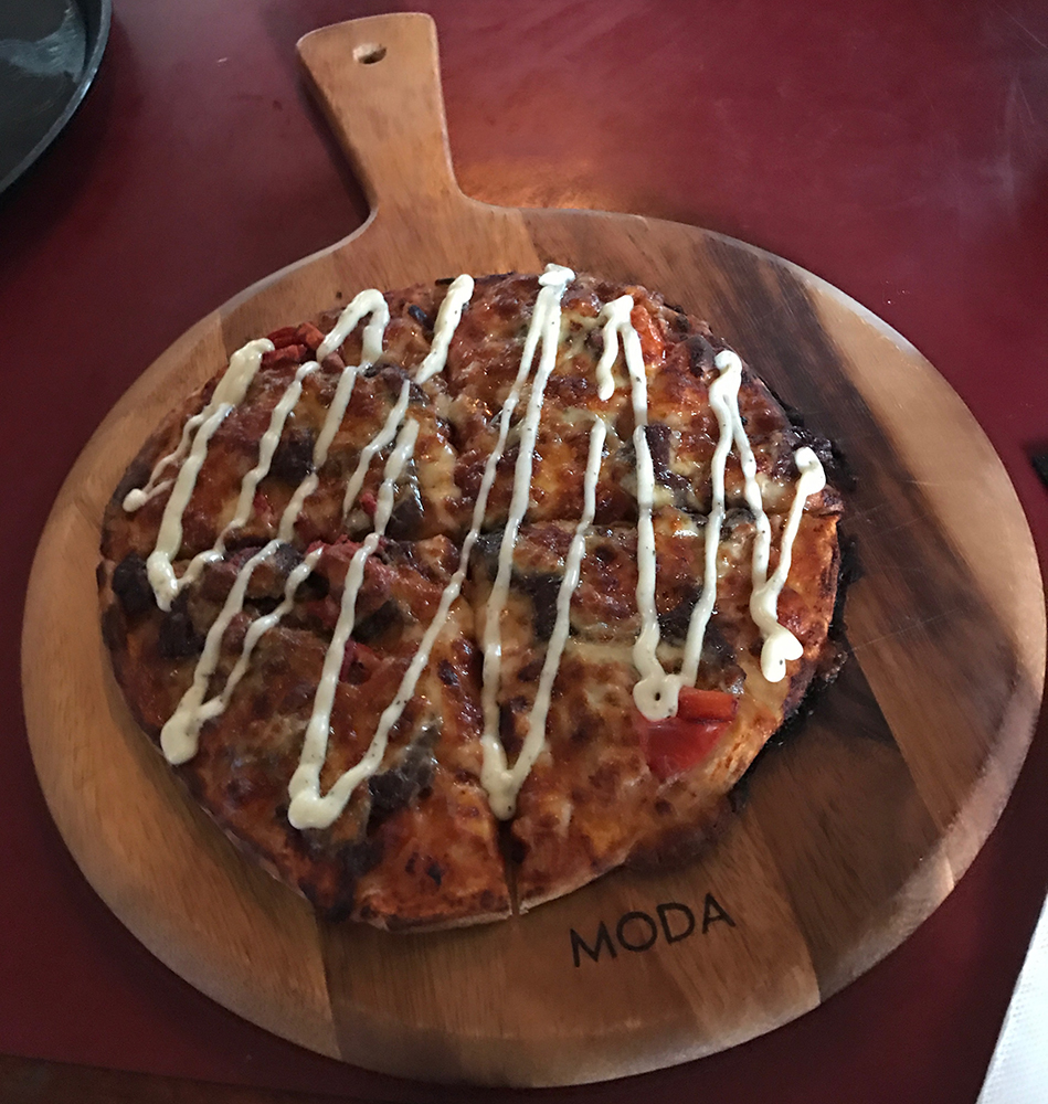 a pizza with white sauce on a wooden board
