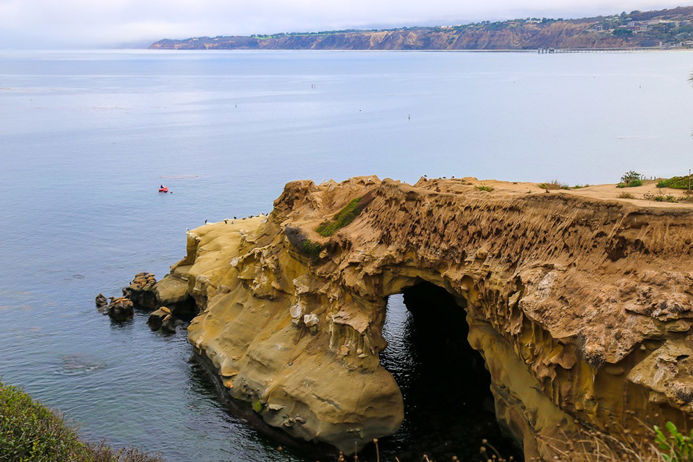 a cliff with a hole in the water
