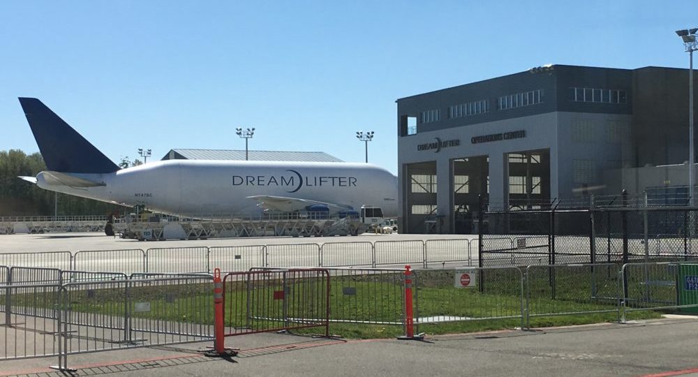 A photo of a Boeing 787 Dreamlifter parked next to a building.