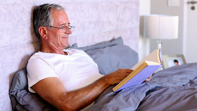 a man reading a book in bed