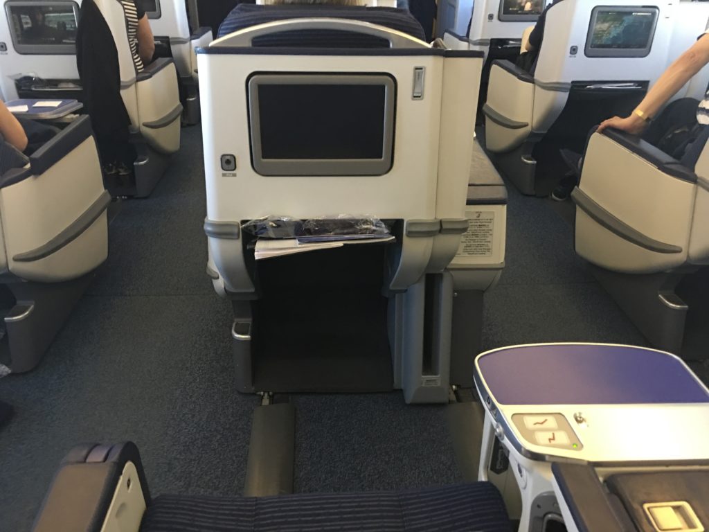 A photo of the back of an ANA business class seat, showing the TV screen and storage pockets.