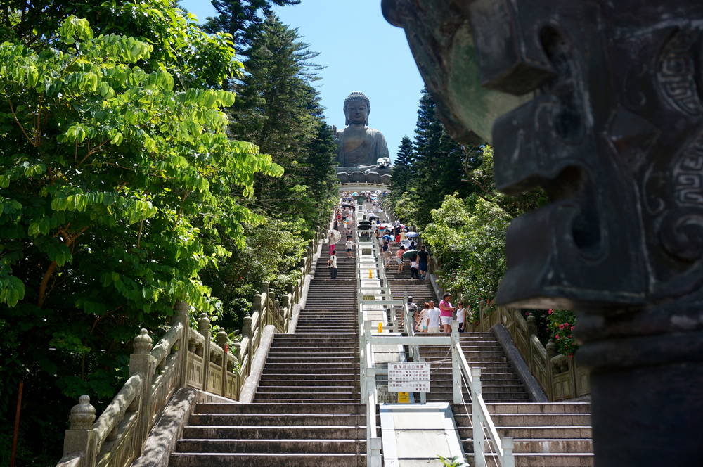 a group of people walking up a staircase with a statue of a buddha