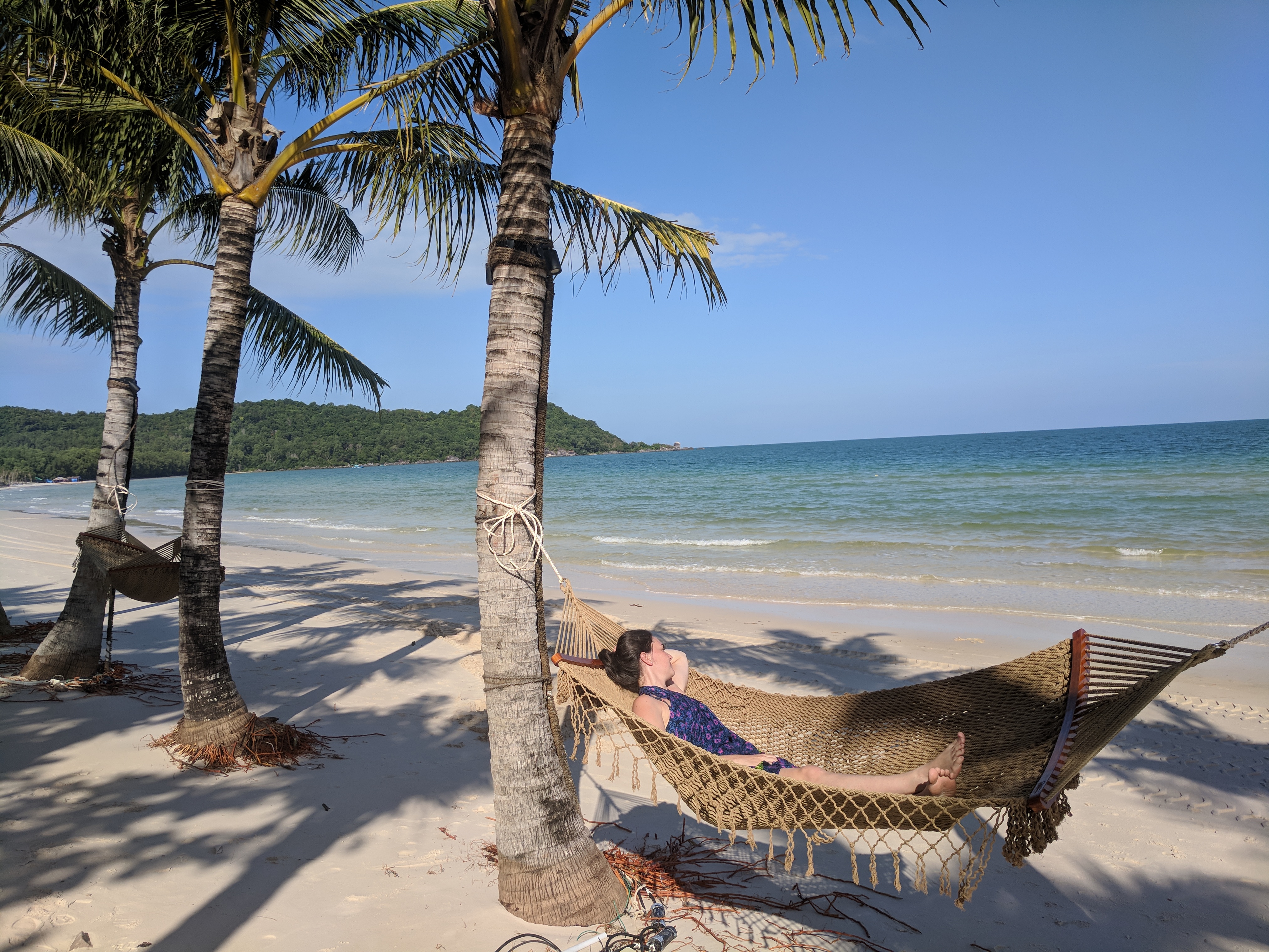 a woman lying in a hammock on a beach