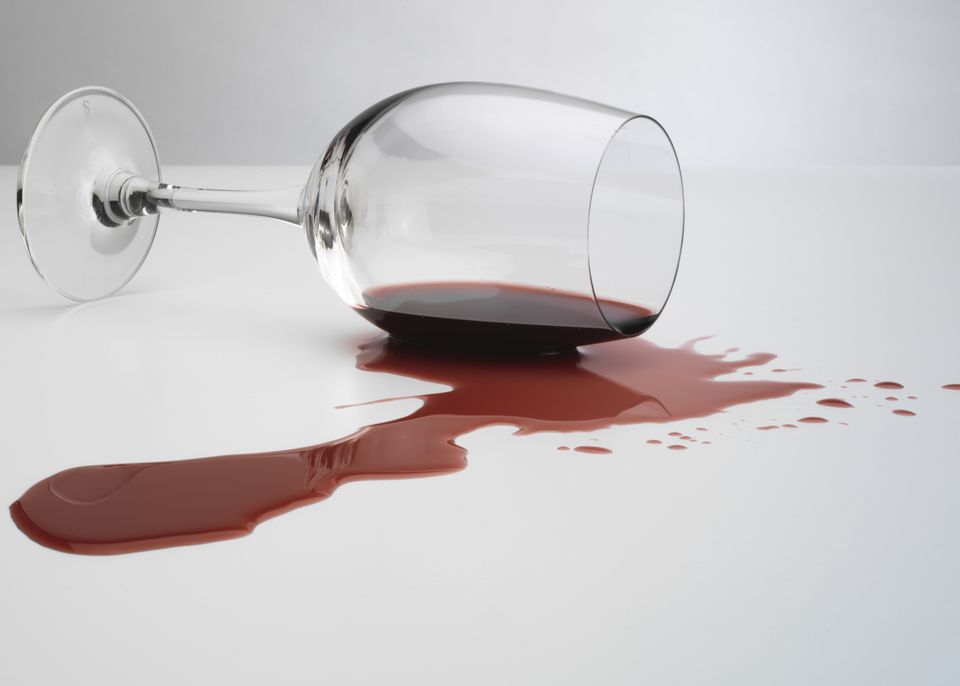 a wine glass with red liquid on the floor