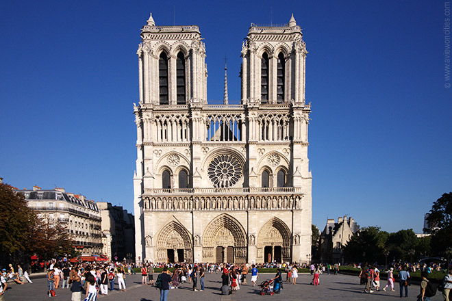 a large white building with towers and people in front with Notre Dame de Paris in the background