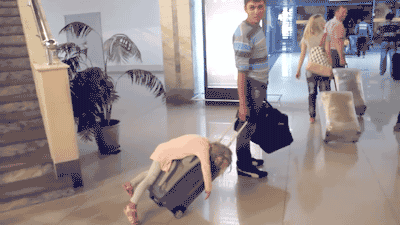 a man pushing a girl on a luggage bag