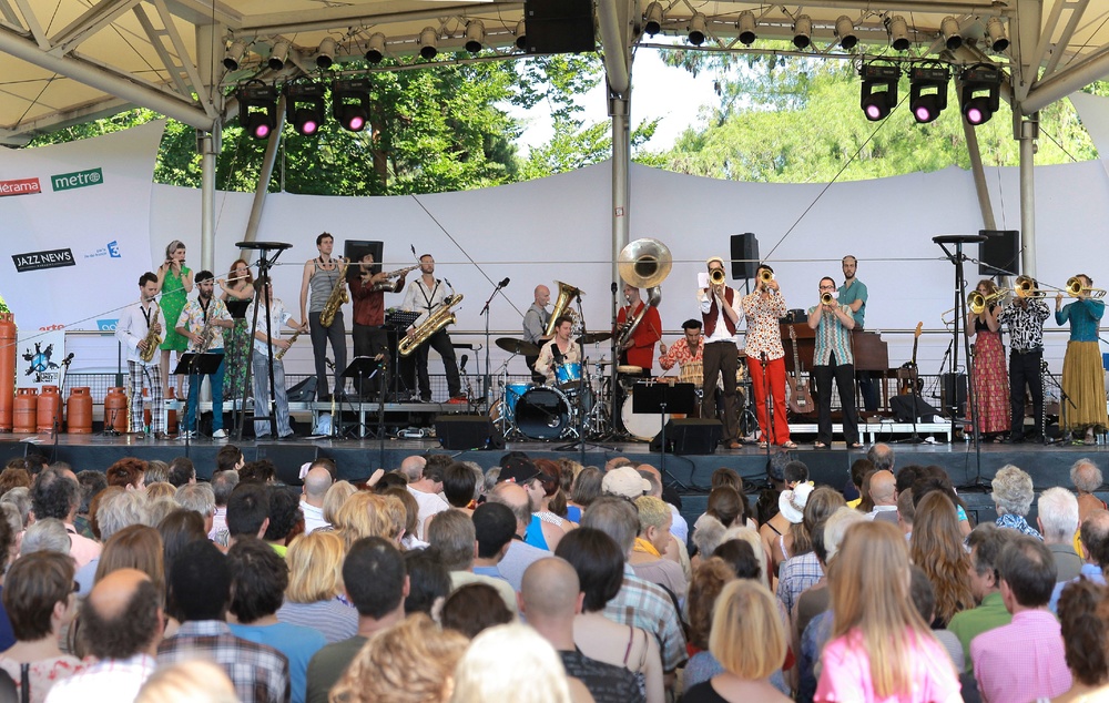 a group of people playing instruments on a stage with a crowd watching