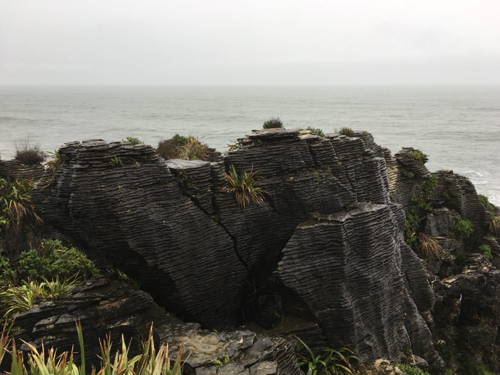 A photo of rock formations with distinctive line patterns where different layers of rock were pressed together, making them resemble a stack of pancakes.
