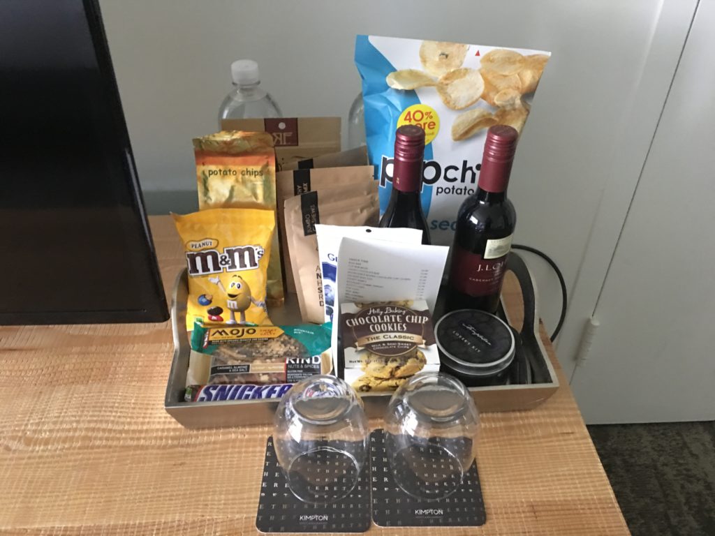 a tray with wine bottles and snacks on a table